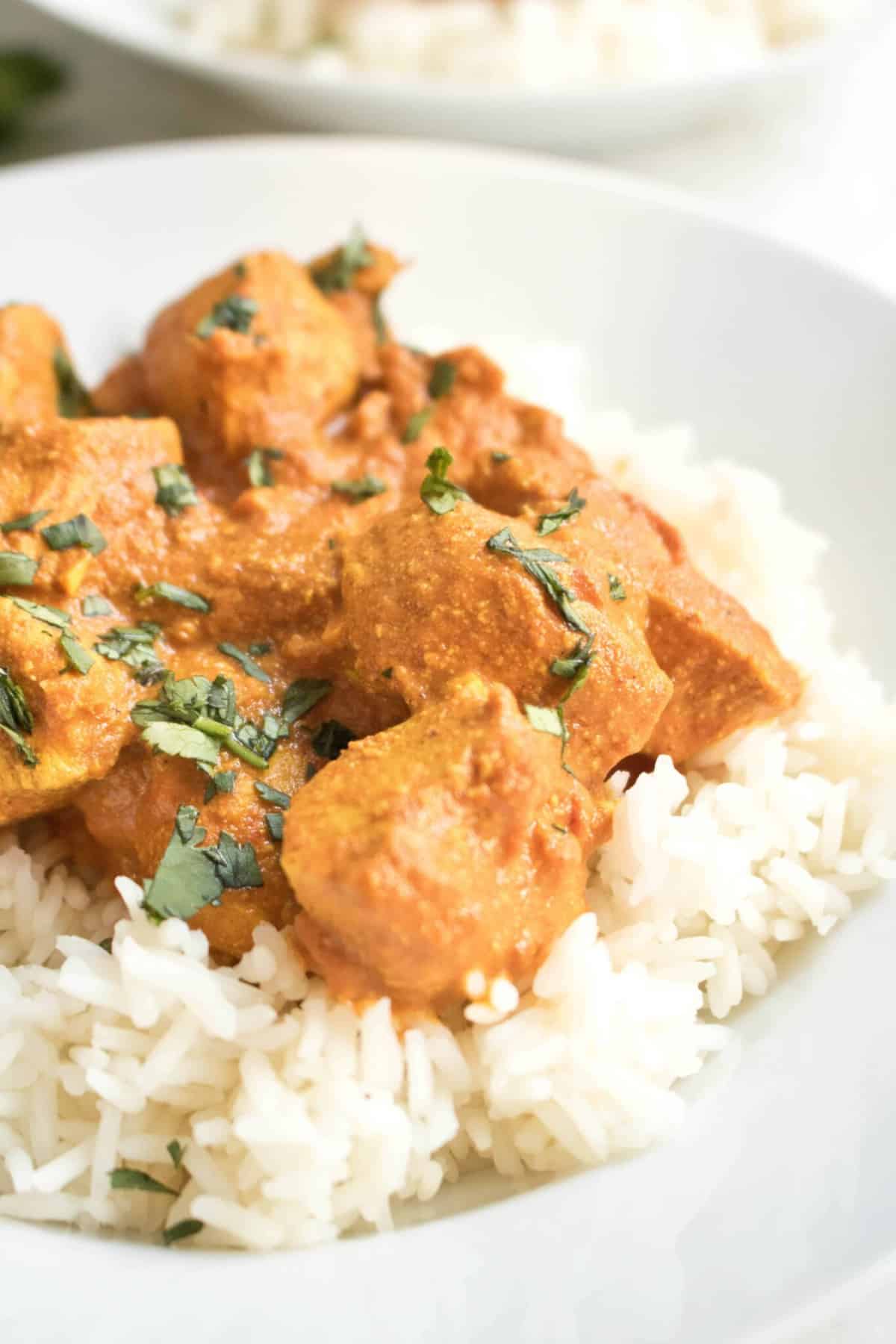 a plate of a bed of rice with chicken tikka masala on top.