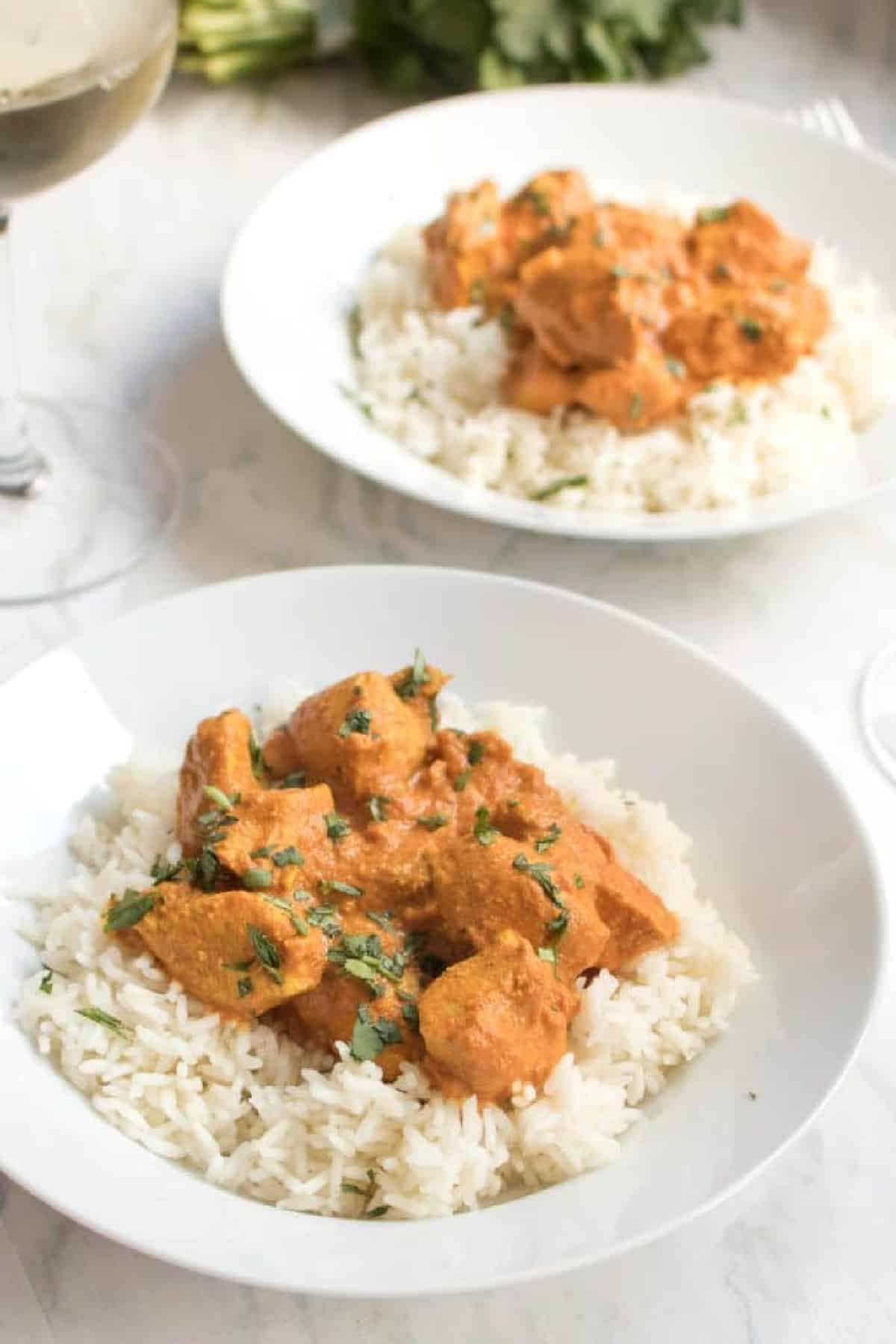 a plate of a bed of rice with chicken tikka masala on top.