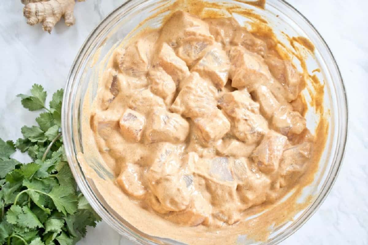 a bowl of cubed chicken in a thick creamy marinade. 