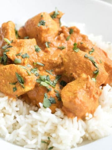 a plate of a bed of rice with chicken tikka masala on top.