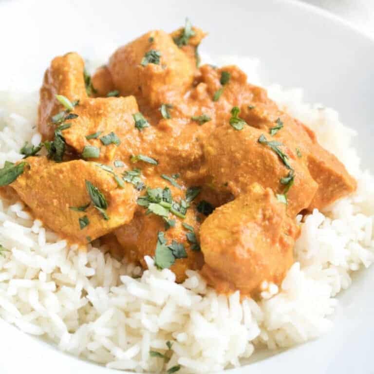 a plate of a bed of rice with chicken tikka masala on top.