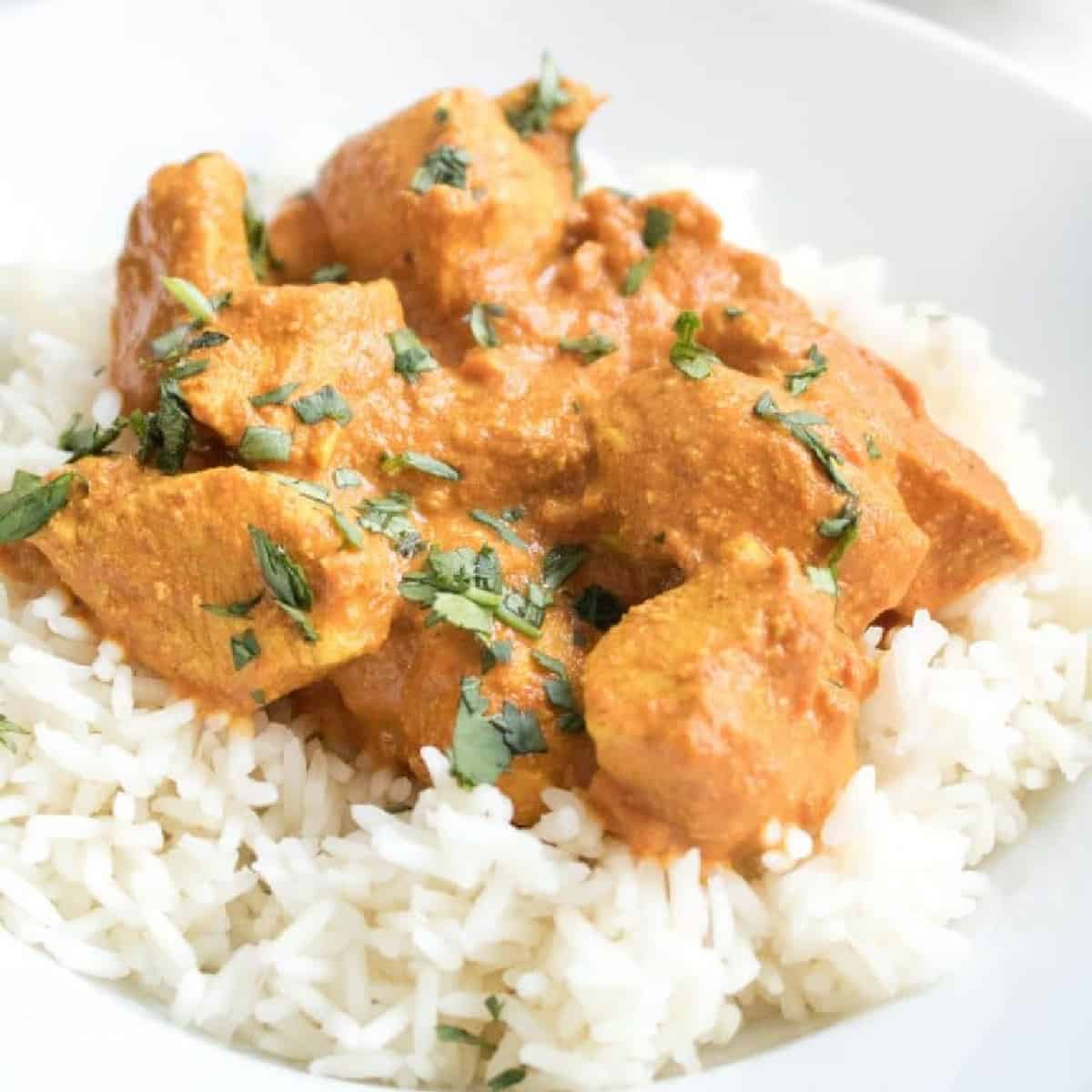 a plate of a bed of rice with chicken tikka masala on top.