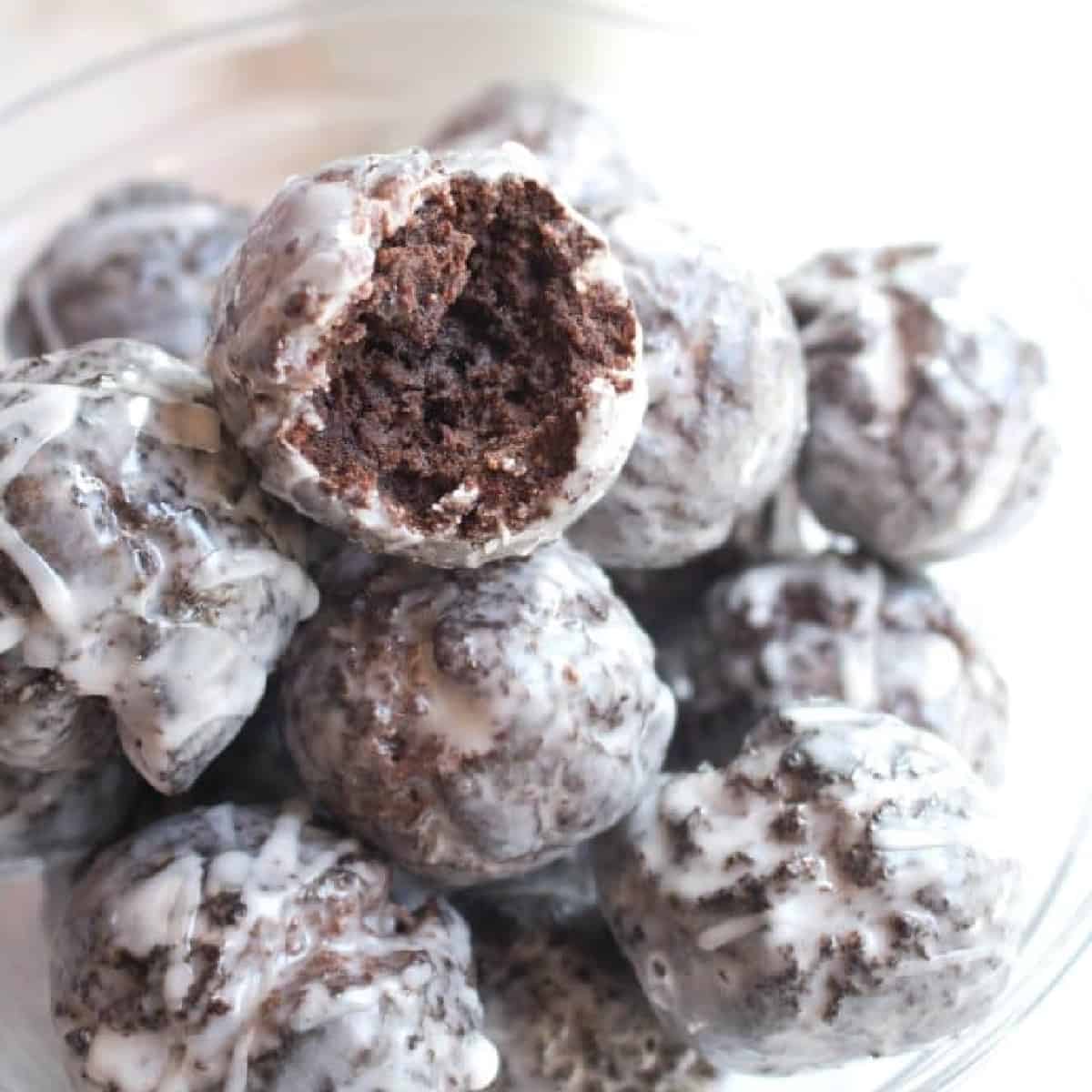 a bowl of chocolate munchkins with one with a bite taken out.