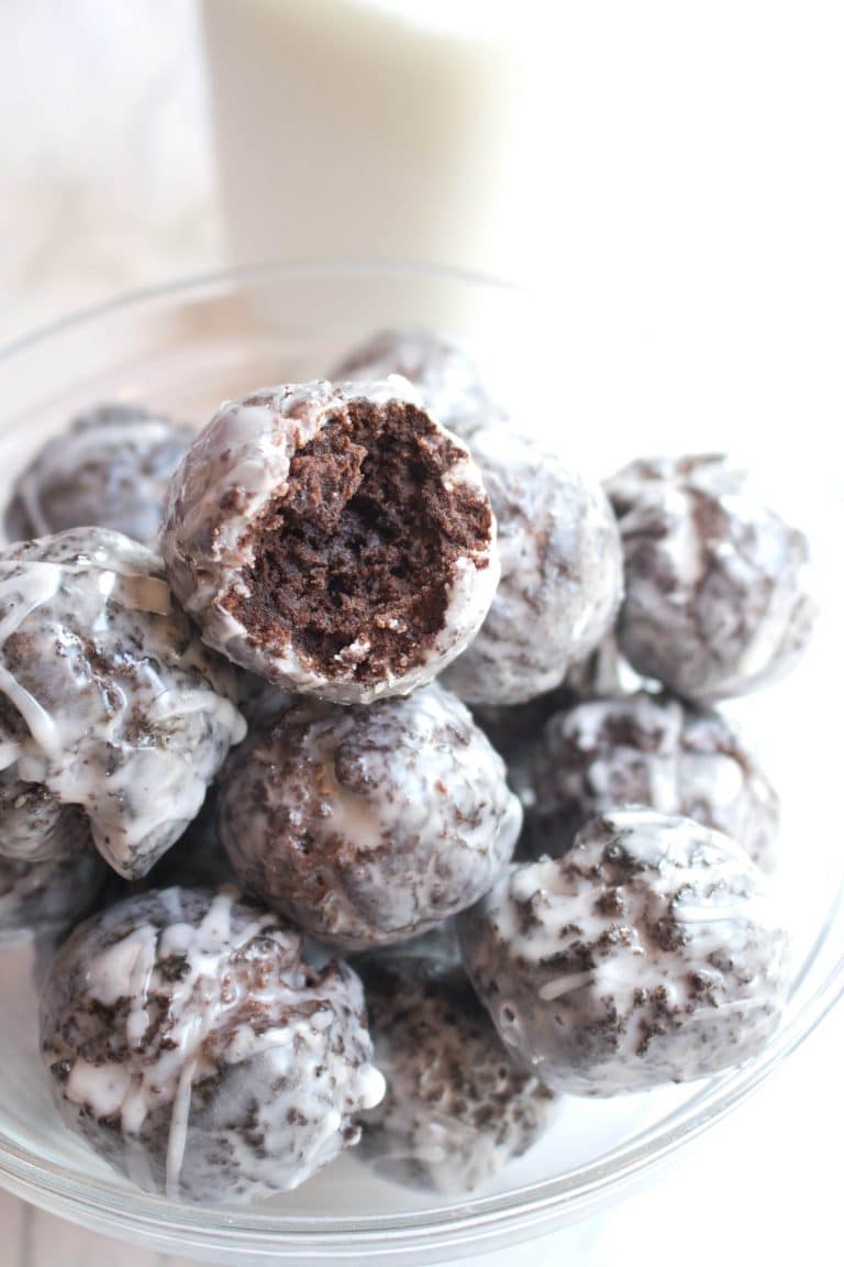 a bowl of glazed chocolate donuts one with a bite taken out