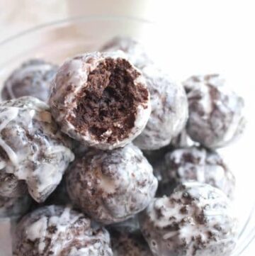 a bowl of glazed chocolate donuts one with a bite taken out