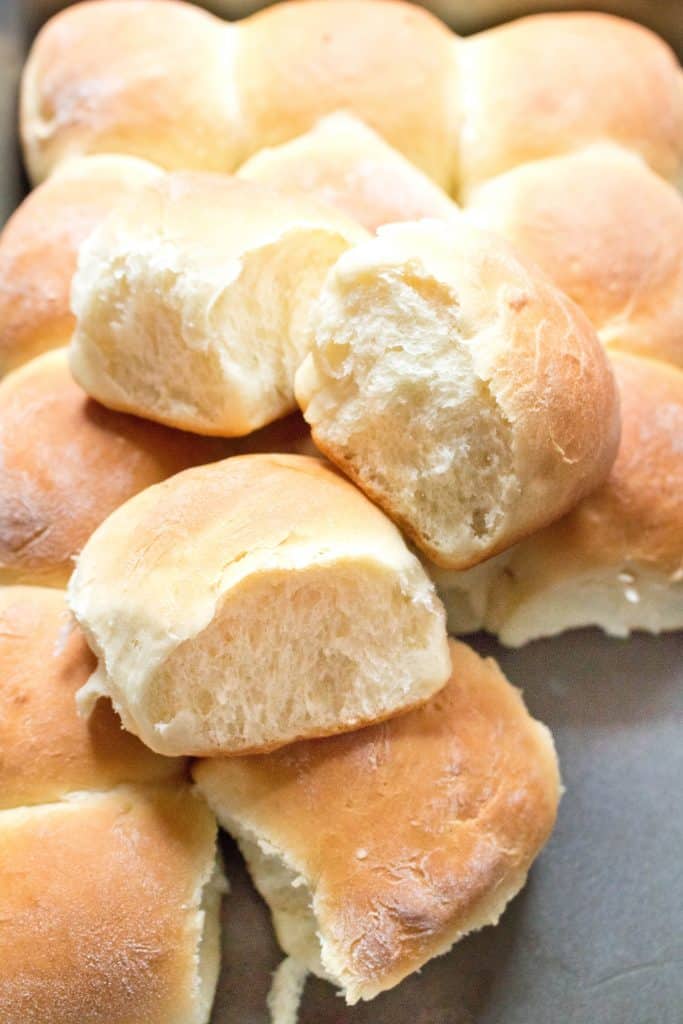 3 dinner rolls pulled from pan on top of other rolls.