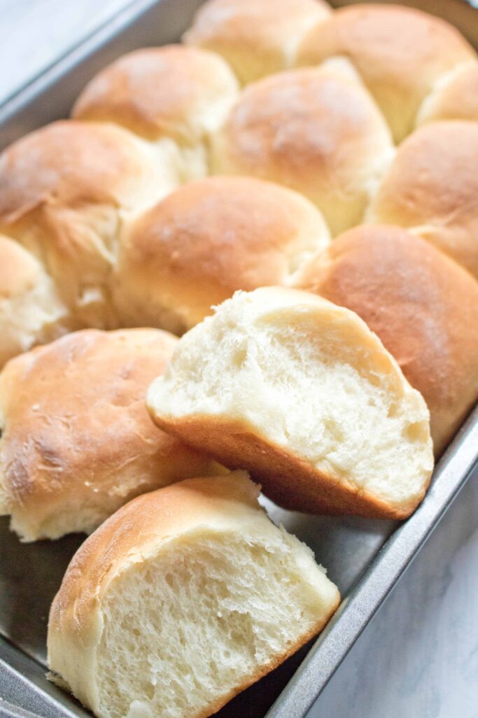 a pan of dinner rolls with two pulled out.