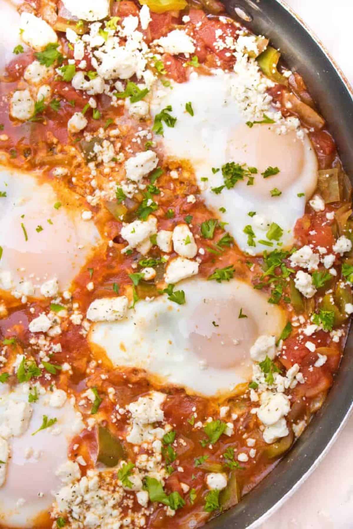 baked eggs in a tomato sauce topped with feta cheese.