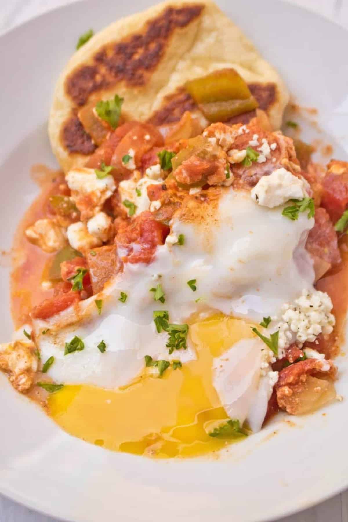 a bowl with naan, tomatoes, and a runny egg.