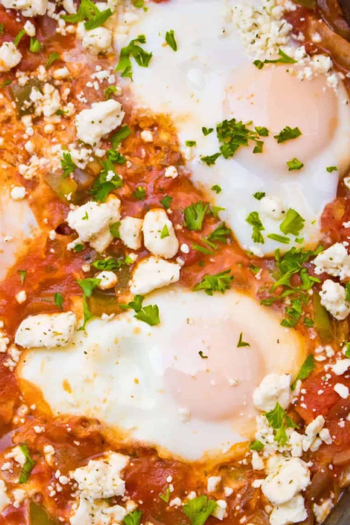 baked eggs in a tomato sauce topped with feta cheese.