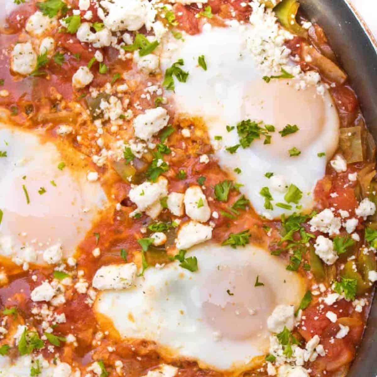 baked eggs in a tomato sauce topped with feta cheese.