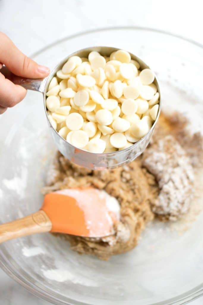 an overhead of white chocolate chips over a bowl of cookie batter