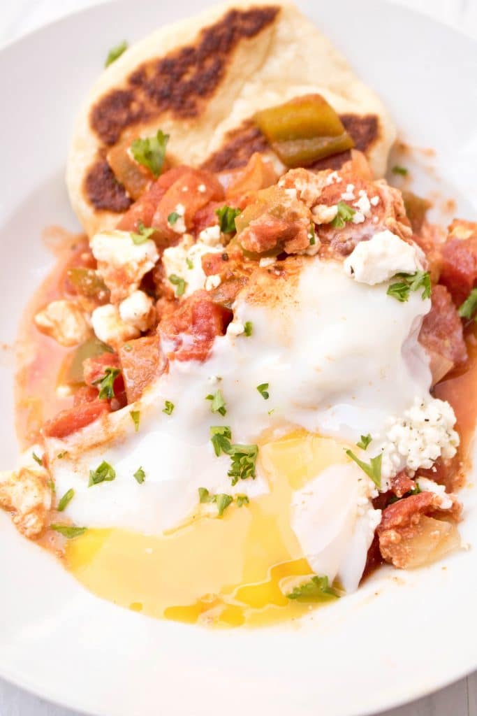 a bowl with naan, tomatoes, and a runny egg.