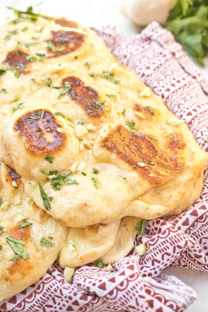 a red napkin with buttery garlic topped naan.