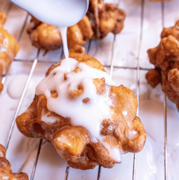 apple fritter being iced with a spoon.