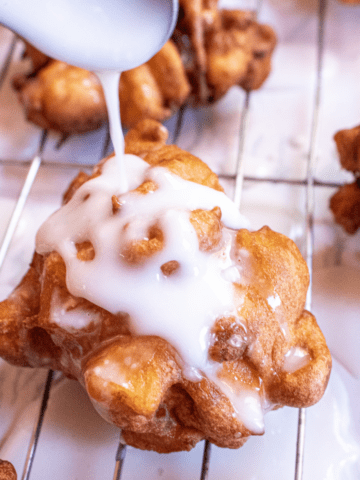 apple fritter being iced with a spoon.