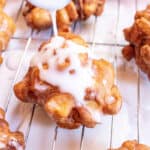 an apple fritter with icing being poured on top.