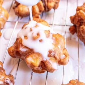 an apple fritter with icing being poured on top.