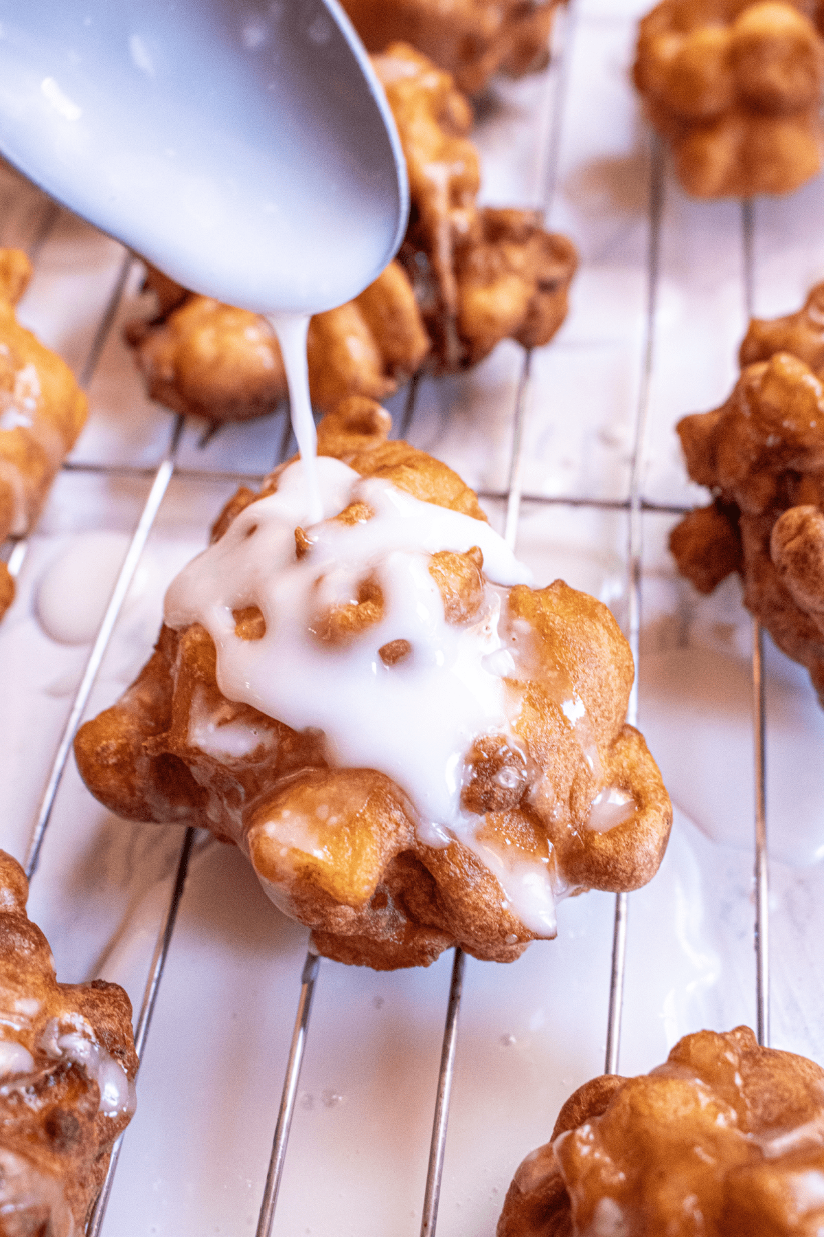 apple fritter being iced with a spoon.