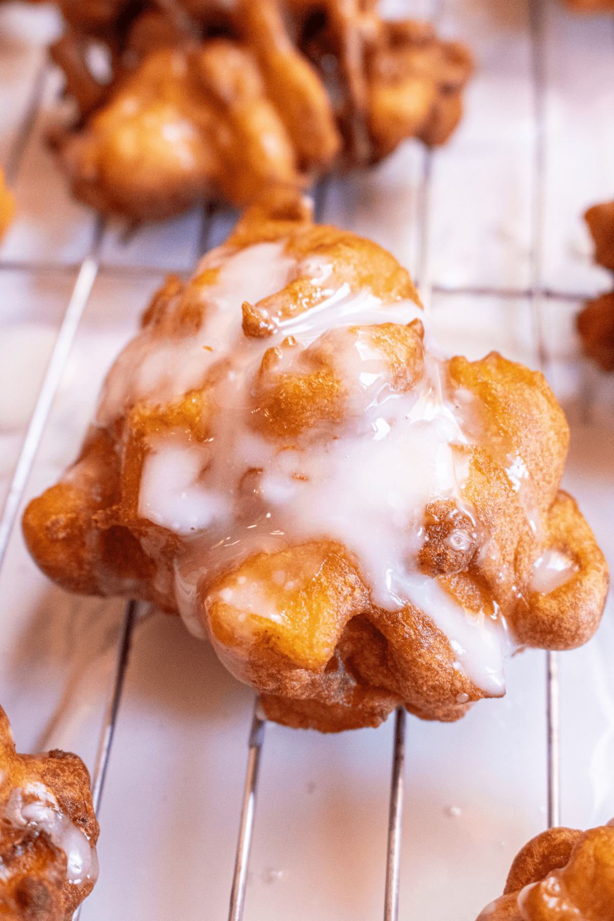 glazed apple fritter on a cooling rack.