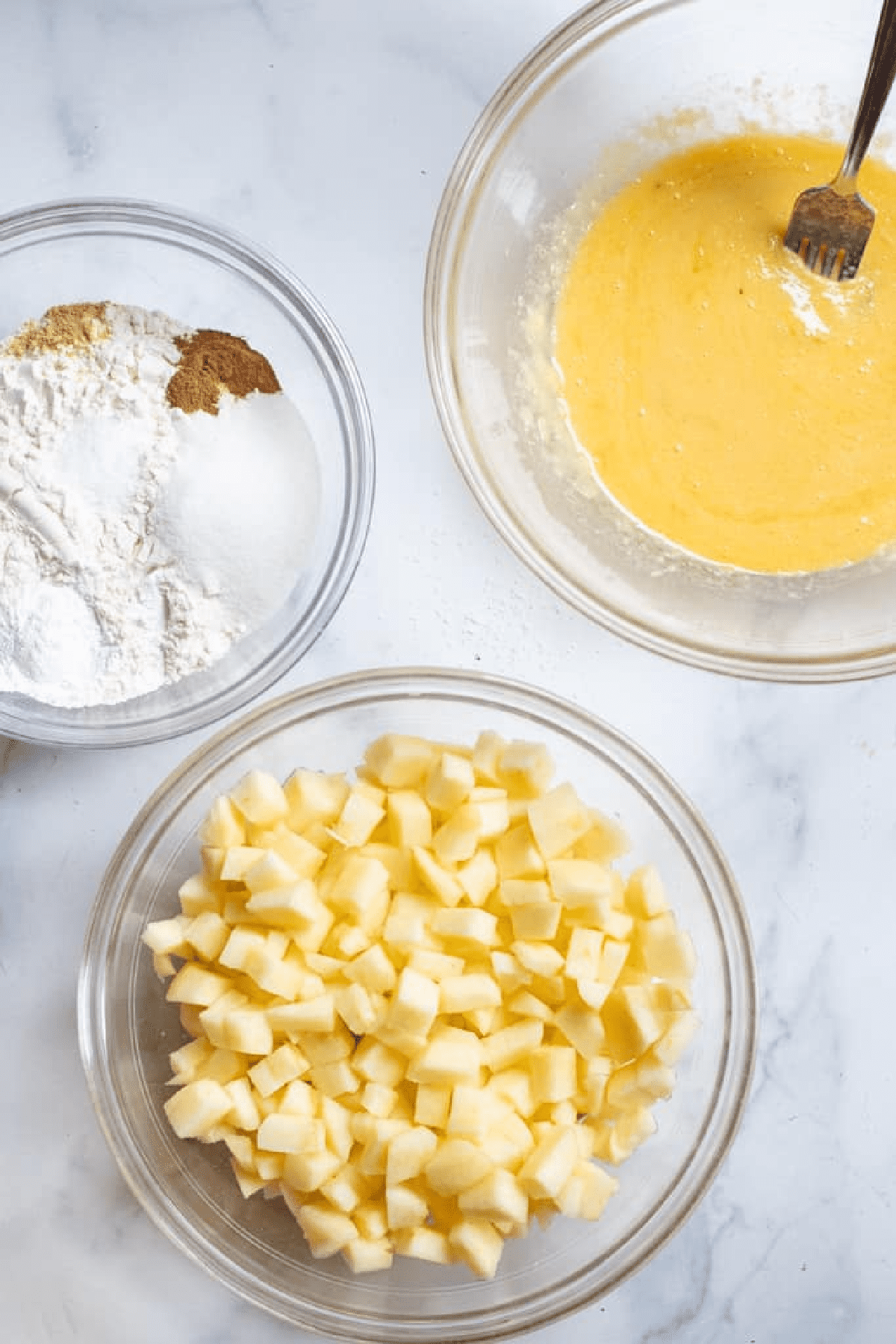 bowls with flour and sugar, diced apples, and egg mixed.