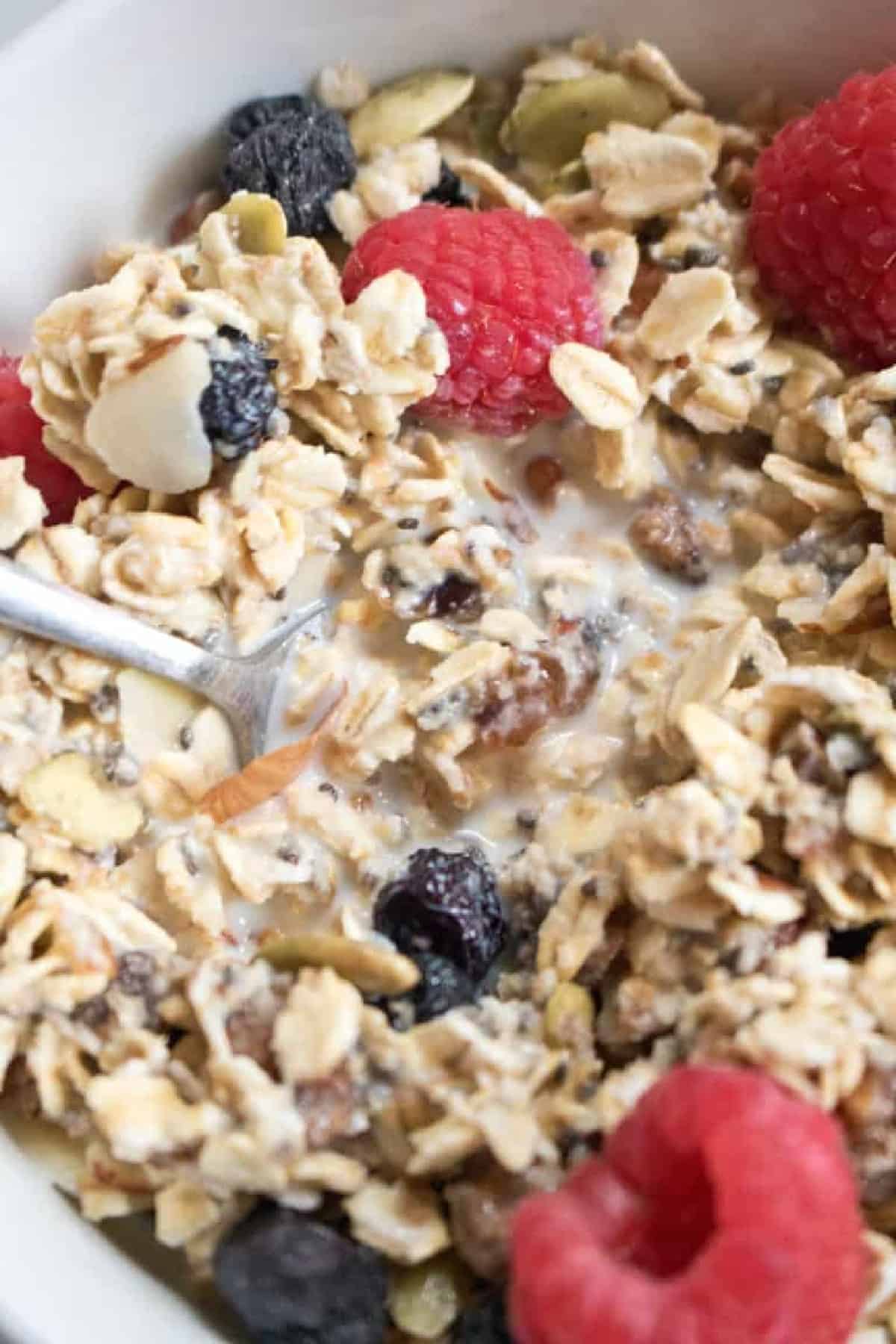 a bowl of museli with fresh fruit on top and a spoon.