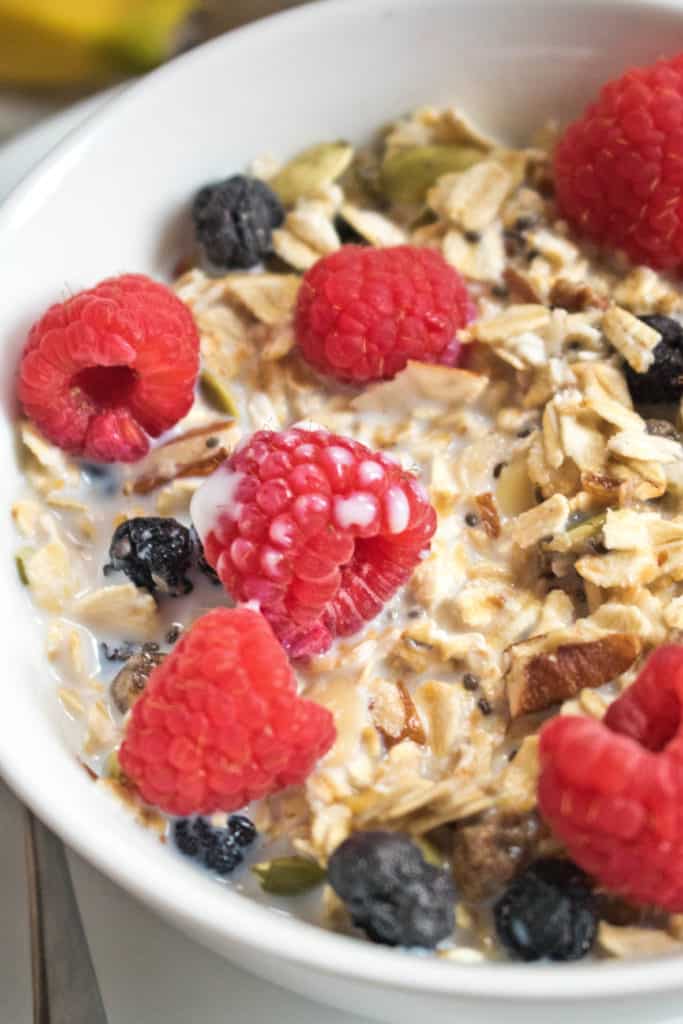a close up of a bowl of muesli with fresh raspberries