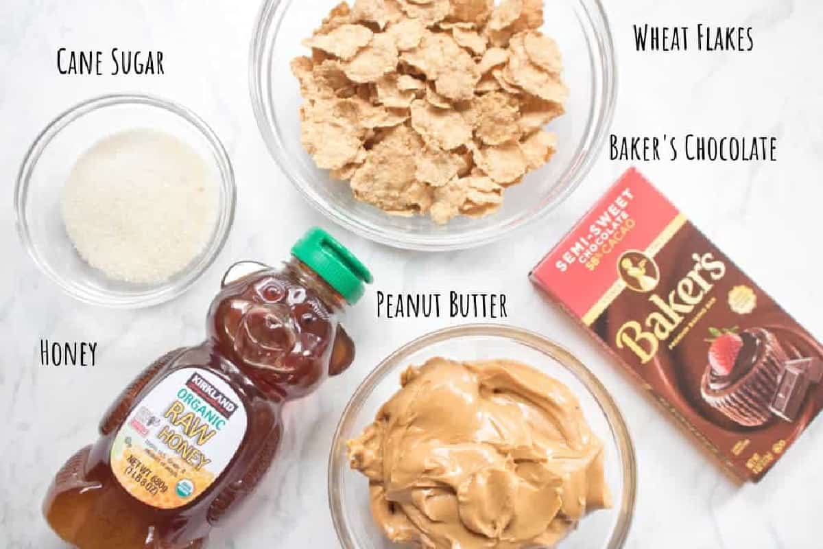 sugar, wheat flakes, baker's chocolate, honey, and peanut butter on counter.