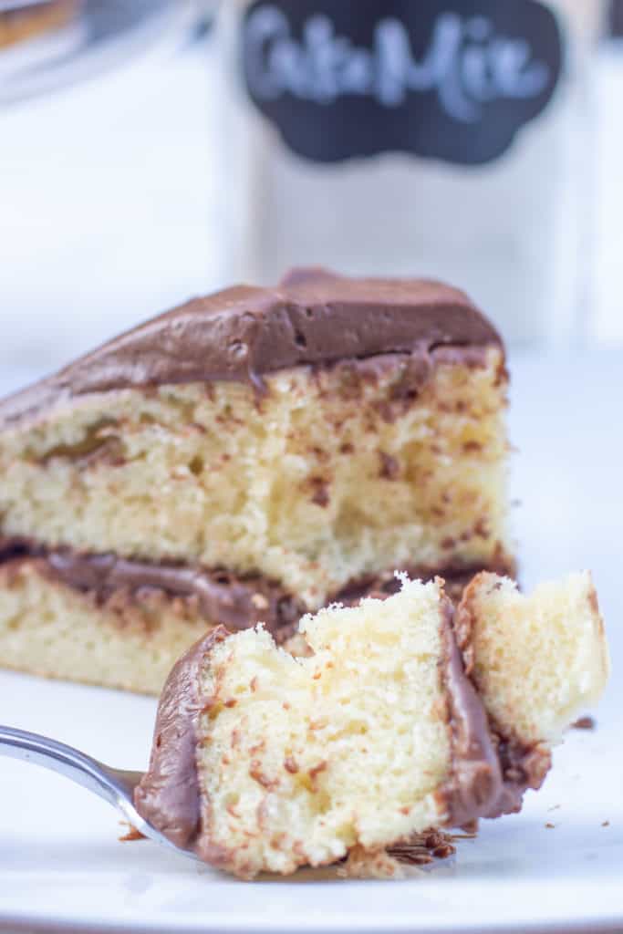 a piece of yellow cake with chocolate frosting with a piece of of it on a fork