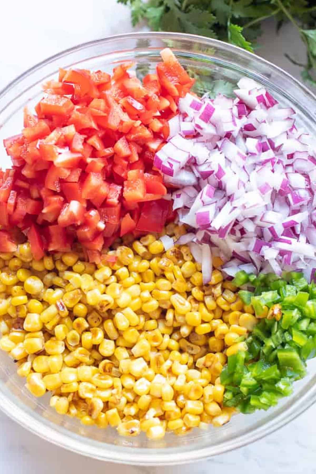 a bow of corn, diced red pepper, diced red onion, diced jalapeno.