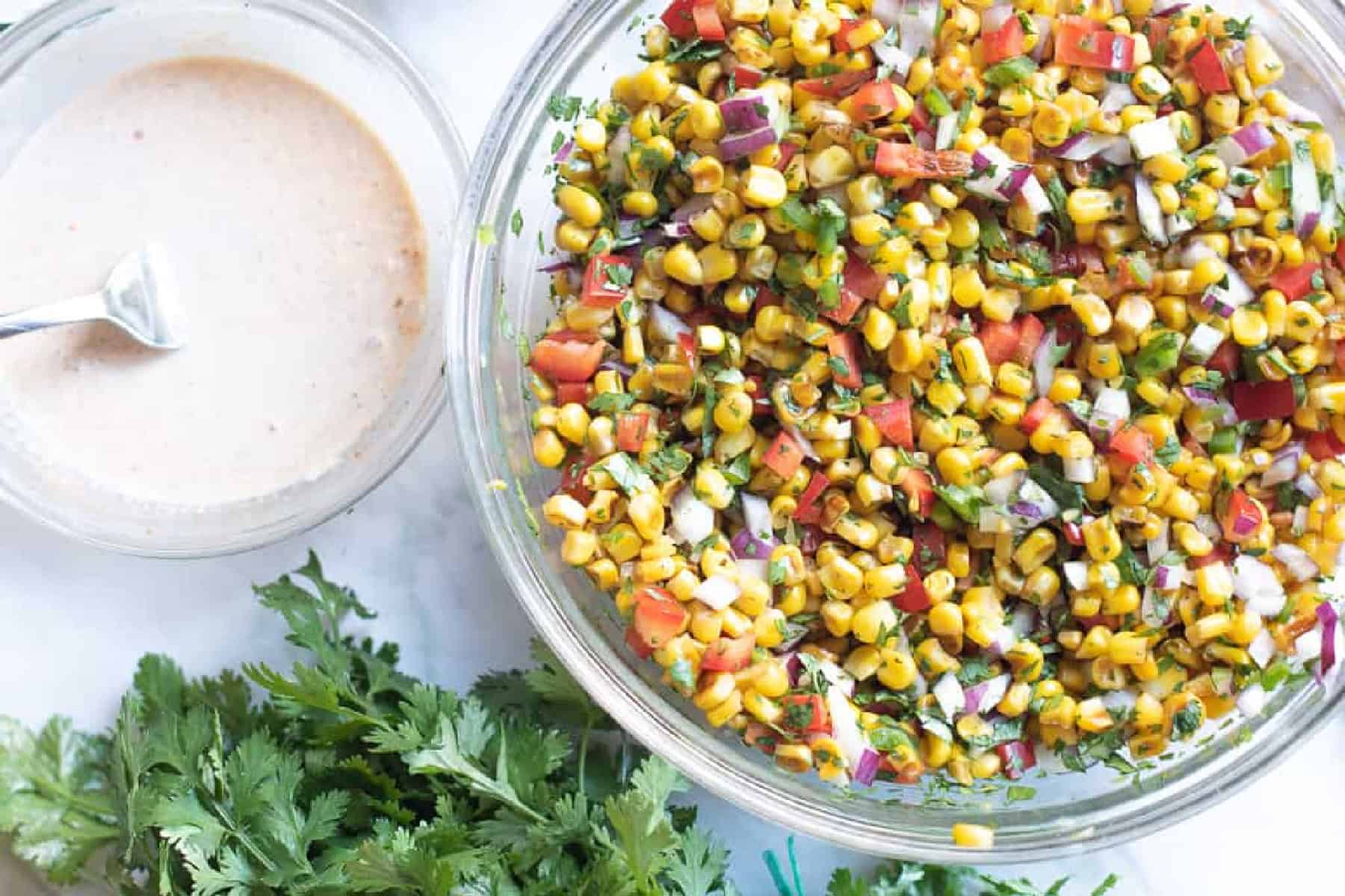 a bowl of mixed dressing and a bowl of mixed corn, pepper, jalapeno, and onion. 