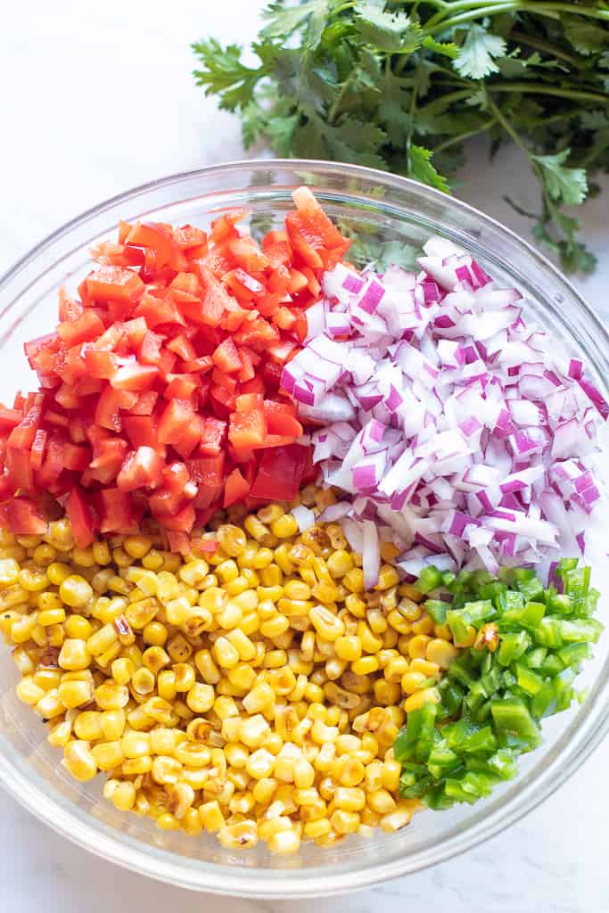 a large bowl of diced tomatoes, onions, corn, and jalapeno.