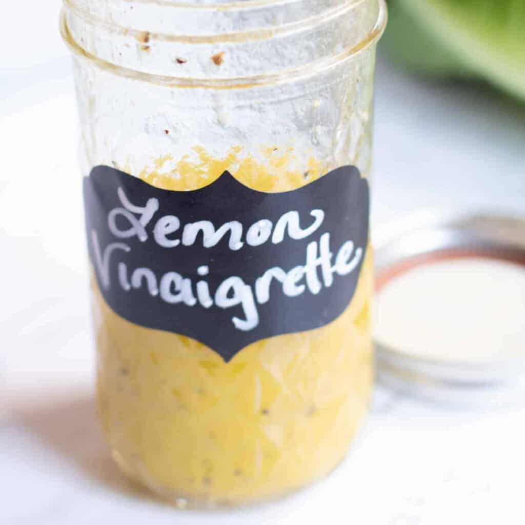 an open mason jar with a label that says Lemon Vinaigrette and vinaigrette in it.