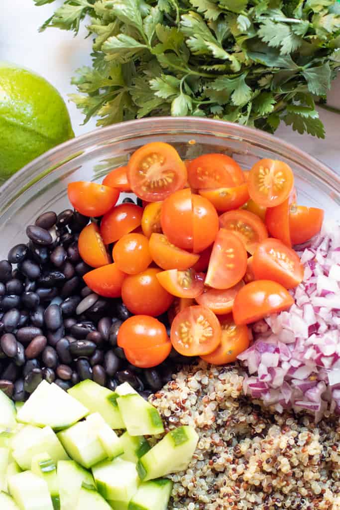 a bowl of black beans, tomatoes, onions, quinoa, and cucumbers