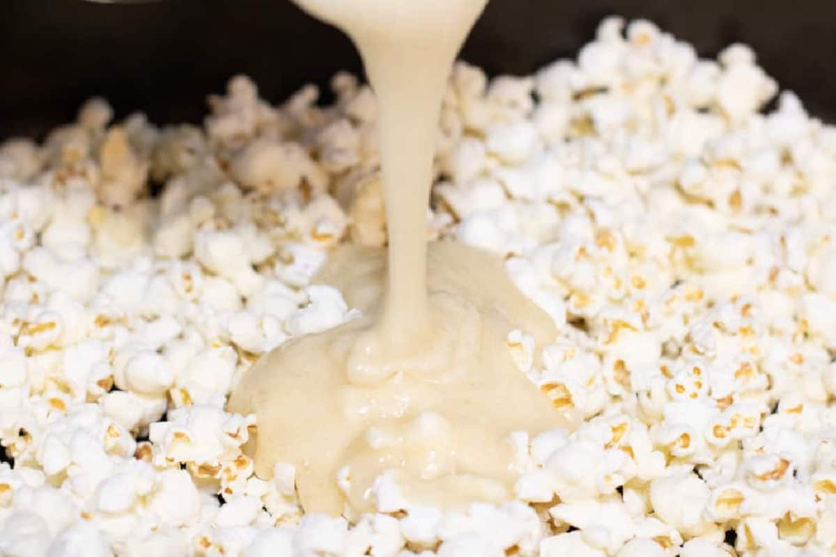 buttery syrup being poured onto popcorn.