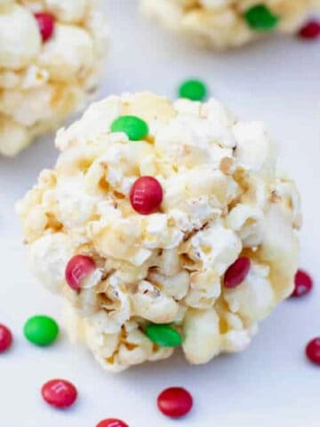 a close up of a popcorn ball with christmas colored m&ms.