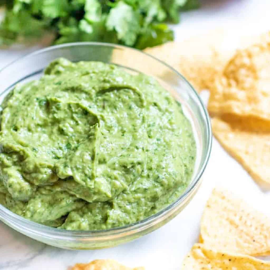 a bowl of avocado with chips on counter.