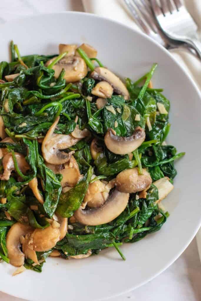 a bowl of cooked spinach and mushrooms