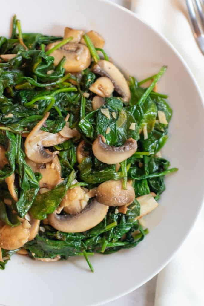 a bowl of cooked spinach and mushrooms