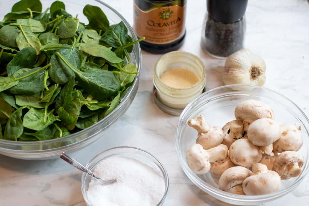 a bowl of spinach, mushrooms, balsamic, onion powder, garlic, and salt on counter