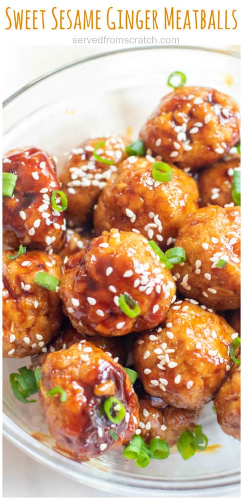 a bowl of sesame seed and green onion topped meatballs