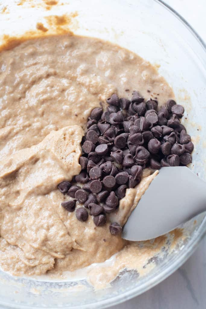 whole wheat muffin batter in a bowl with chocolate chips being folded in