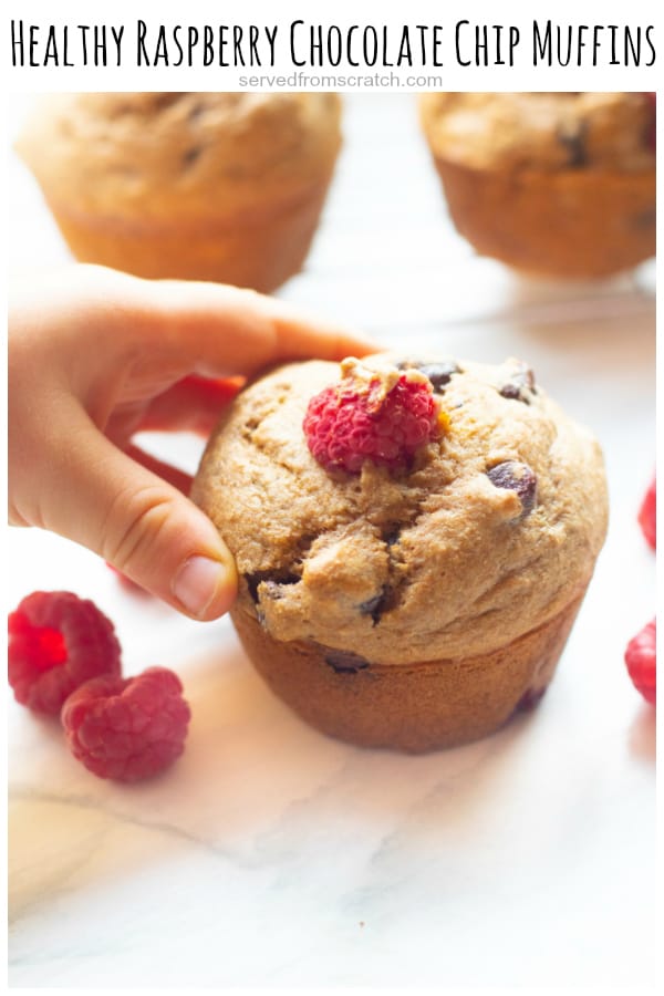 a baby hand holding a raspberry chocolate chip muffin with Pinterest pin text.