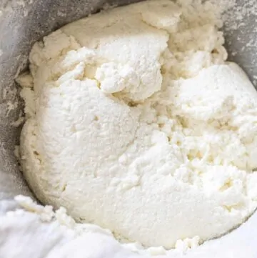 fresh made ricotta cheese in a cheese cloth in a colander.