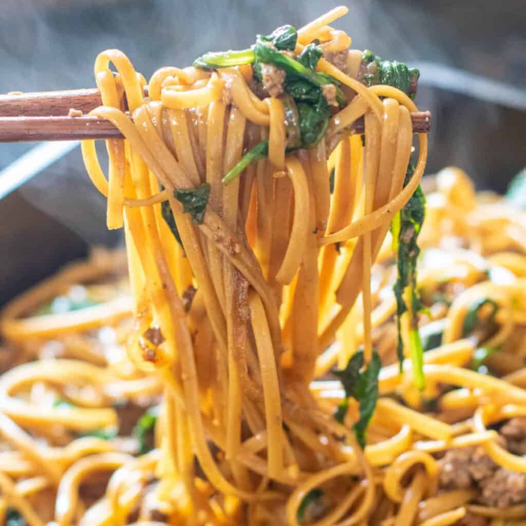 beef and spinach noodles in chopsticks.