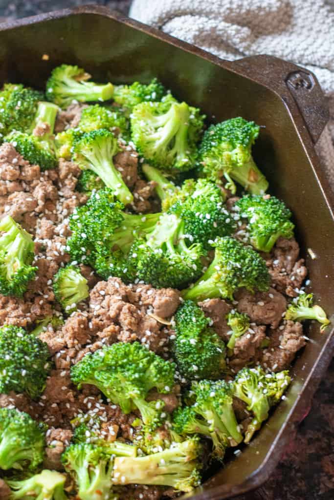 cooked ground beef and broccoli with sesame seeds in a cast iron.