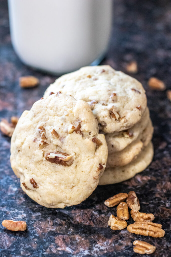 baked pecan sandies stacked on counter with pecans