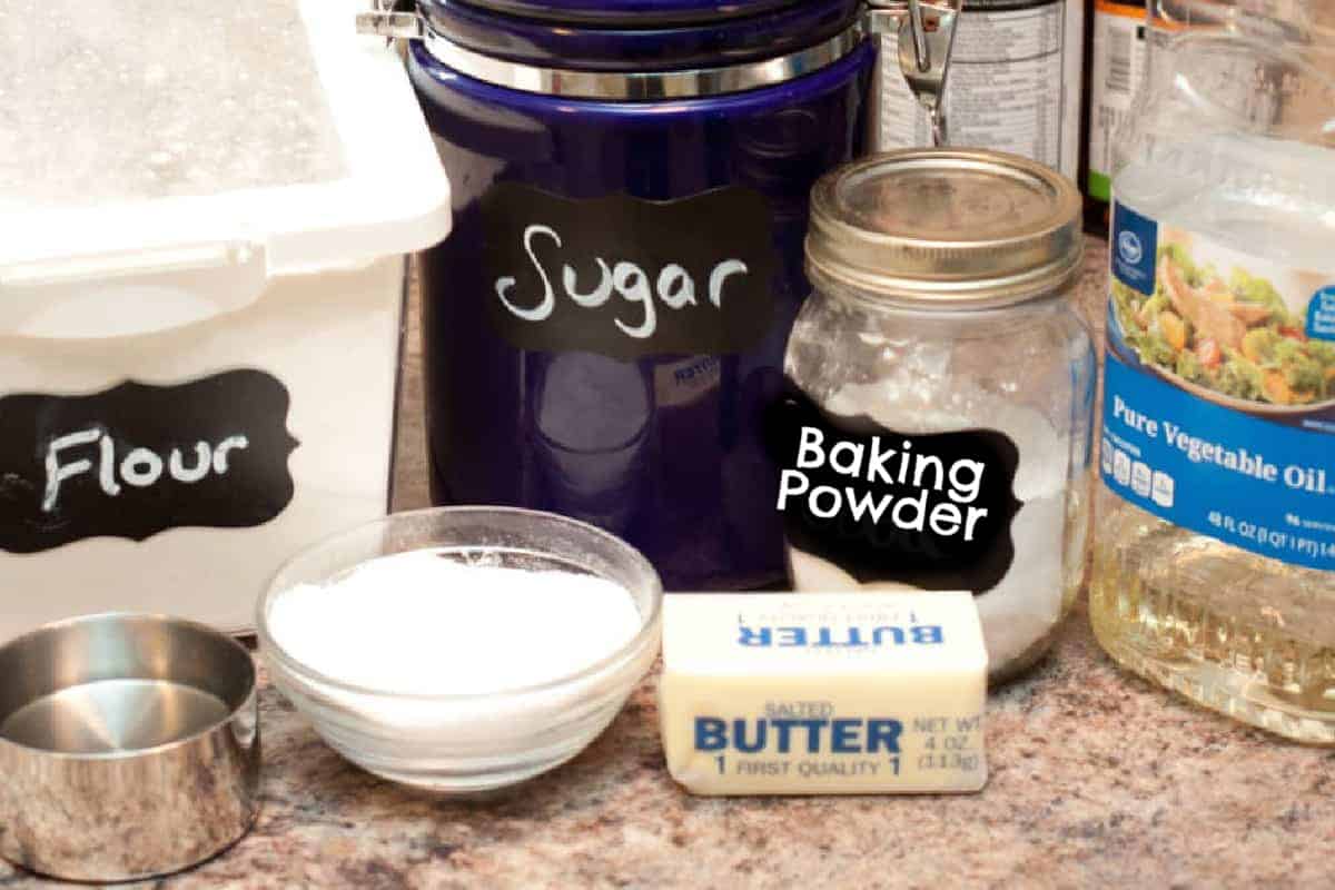 flour, sugar, baking powder, oil, salt, and butter on a counter.