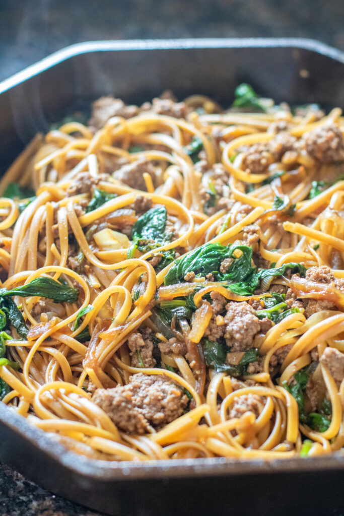 noodles with spinach and ground beef in a cast iron