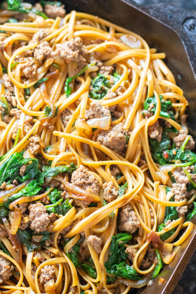 linguine noodles with spinach and ground beef in a cast iron